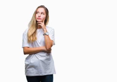 Çene düşünme hakkında soru, dalgın ifade üzerine el ile izole arka plan üzerinde rahat beyaz t-shirt giyen genç güzel sarışın bir kadın. Düşünceli yüzüyle gülümsüyor. Şüphe kavramı.