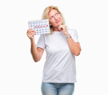 Adet takvim izole ver arka plan ciddi bir yüz düşünme hakkında soru, çok karışık fikir tutan orta yaş sarışın kadın