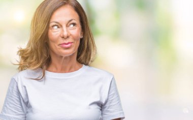 Orta yaş üst düzey İspanyol kadın görünümlü yan ve dik dik bakma uzağa düşünce gülümseyen izole arka plan.