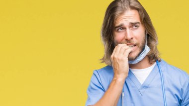 Genç yakışıklı Doktor adam stresli ve gergin elle çivi ısırma ağzına bakarak izole arka plan üzerinde uzun saçlı. Anksiyete sorunu.