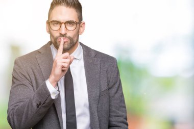 Genç yakışıklı iş adamı dudaklarında parmak ile sessiz olmanı izole arka plan üzerinde. Sessizlik ve gizli kavramı.