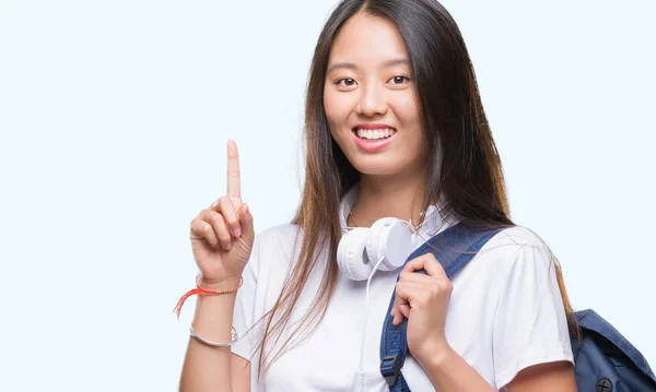 若いアジア女性の身に着けているバックパックとヘッドフォンを分離アイデアや質問 ナンバーワンの幸せそうな顔で指を指していると驚かれる背景 — ストック写真