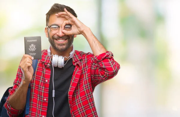 指の間から見て目に手で サインをして笑っている幸せそうな顔で孤立した背景にアメリカの大人のヒスパニック学生男持株パスポート — ストック写真