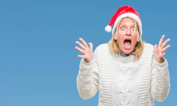 中年金髪女性をクリスマスの帽子をかぶって狂気を祝う背景を分離した腕を上げると成功のためびっくりし 叫んで興奮して目を開きます 勝者の概念 — ストック写真