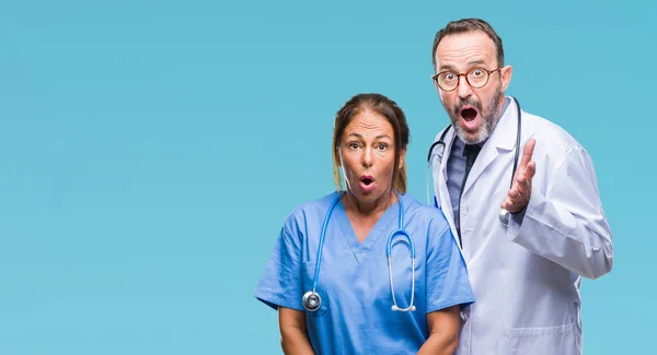 中年西班牙医生伴侣夫妇穿着医疗制服在孤立的背景恐惧和震惊与惊喜的表情 恐惧和兴奋的脸 — 图库照片