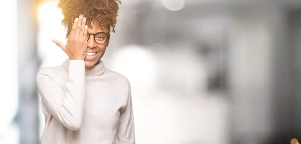 美丽的年轻非洲裔美国妇女戴眼镜在孤立的背景覆盖一只眼睛与自信的微笑在脸上和惊喜的情感 — 图库照片