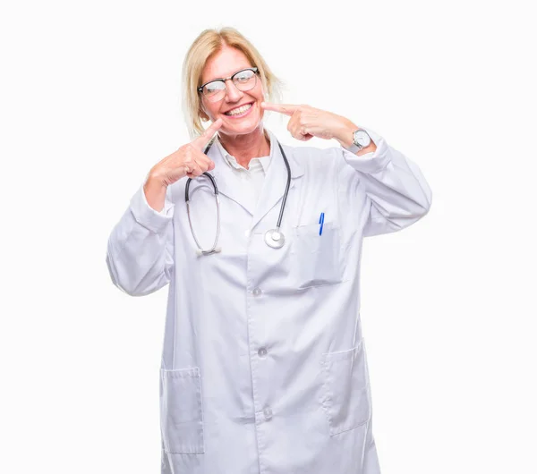 中年金发碧眼的医生妇女在孤立的背景微笑自信显示和指向用手指的牙齿和嘴 健康理念 — 图库照片