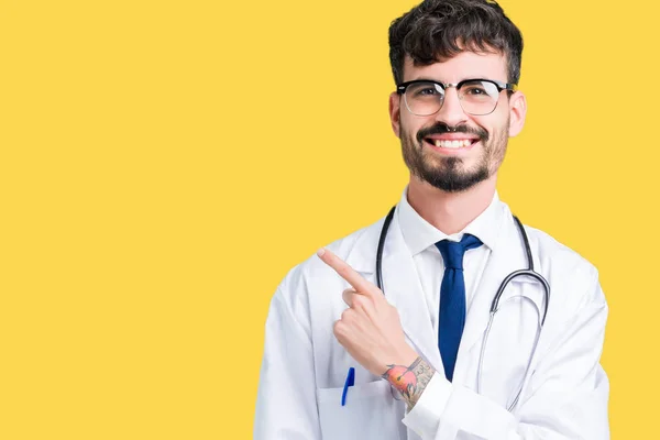 若い医者の手と顔に幸せで自然な表現のある側までの指で指している顔の笑顔で陽気な分離の背景の上病院コートを着た男 — ストック写真