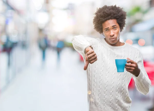 Afro american man drinking cup of coffee over isolated background with angry face, negative sign showing dislike with thumbs down, rejection concept