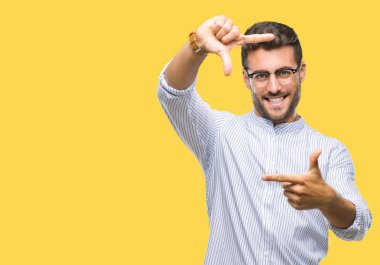 Yakışıklı delikanlı elle yapma çerçeve ve parmakları ile mutlu yüz gülümseyen izole arka plan üzerinde. Yaratıcılık ve Fotoğrafçılık kavramı.