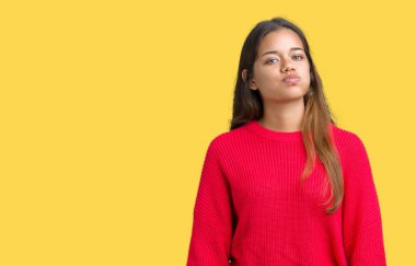 Komik surat ile yanakları şişirme izole arka plan üzerinde kırmızı kış kazak giyen genç güzel esmer kadın. Ağız ile hava, deli ifade şişirilmiş.