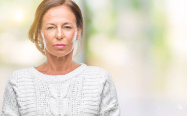 Yüzünde ciddi bir ifade ile izole arka plan üzerinde kış kazak giyen orta yaş üst düzey İspanyol kadın. Basit ve doğal kameraya bakıyor.