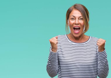 İzole arka plan kutlama üzerinde orta yaş İspanyol kadın kıdemli şaşırttı ve başarı için kaldırdı kollarını açarak hayret ve gözleri açık. Kazanan kavramı.