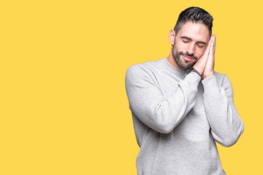 Uyku yorgun hayal ve ellerle birlikte poz ile kapalı gözler gülümseyen izole arka plan üzerinde sweatshirt giyen genç yakışıklı adam.