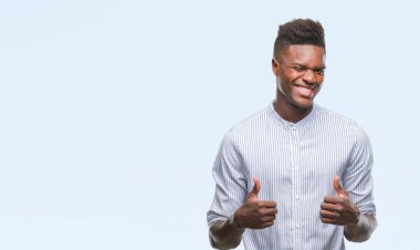 İzole arka plan başarı işareti el ile olumlu hareketi yaparken genç Afro-Amerikan adam başparmak gülümseyen ve mutlu. Neşeli bir ifadeyle, kazanan jest kameraya bakıyor.