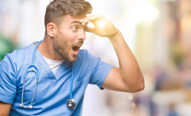 Genç yakışıklı Doktor cerrah adam izole arka plan çok mutlu ve gülümseyen uzakta el ile üzerine kafa arıyorum. Arama kavramı.