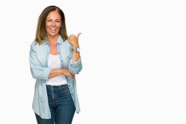 Orta yaş yetişkin kadın arıyorum ve başparmak yanında yukarıyı mutlu yüz ile gülümseyen izole arka plan üzerinde rahat kot gömlek giymiş.