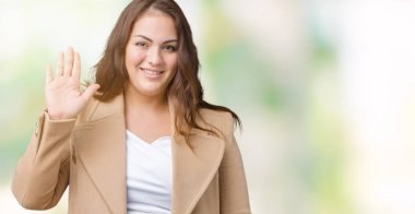 Güzel kış ceket izole arka plan Waiving mutlu selam söyleyerek üzerinde ve gülümseyen, dostça karşılama jest giyen boyutu genç kadın artı