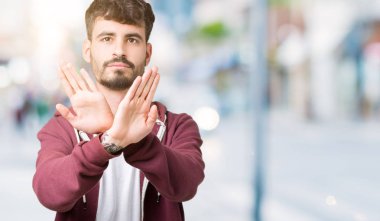 Yakışıklı delikanlı izole arka plan ret ifade geçiş silah ve avuç içi eksi işareti, kızgın surat yapıyor