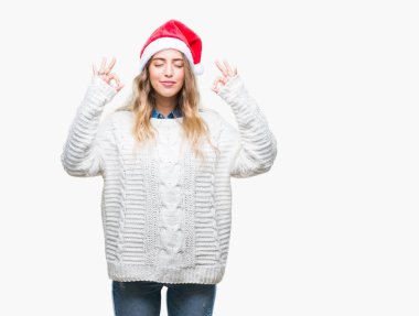Güzel sarışın genç kadın giyen Noel şapka izole arka plan üzerinde dinlenmek ve gülümseyen gözlerle kapalı parmak jestle meditasyon yapıyor. Yoga kavramı.