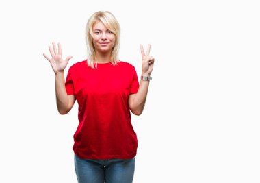 Gösterilen ve parmakları ile işaret izole arka plan üzerinde kırmızı t-shirt giyen genç güzel sarışın kadın kendinden emin ve mutlu gülümseyerek süre yedi numara.