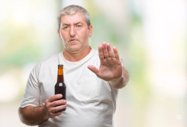 Üst düzey yakışıklı açık eliyle dur işareti ile ciddi ve kendine güvenen ifade, savunma jest yapıyor izole arka plan üzerinde bira şişesi içme