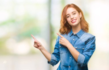 Gülümseyen ve iki elleri ve parmakları ile tarafına işaret kamera bakarak izole arka plan üzerinde genç güzel kadın.