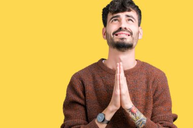 Genç yakışıklı adam yalvarıyor ve umut ifade yüzünde çok duygusal ve endişe ile birlikte elleriyle dua izole arka plan üzerinde kış kazak giyiyor. Bağışlanmak. Din kavramı.