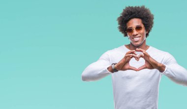 Afro Amerikalı adam aşık kalp simgesi ve elleriyle şekil gösteren gülümseyen izole arka plan üzerinde güneş gözlüğü takıyor. Romantik kavramı.