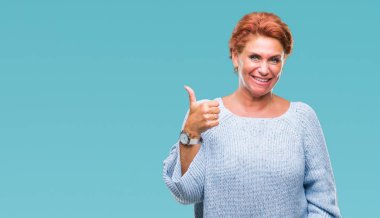 Atrractive üst düzey beyaz Kızıl saçlı kadın hareketi el ile mutlu yaşasın yapıyor izole arka plan üzerinde kış kazak giyiyor. Kameraya bakarak başarı gösteren ile ifade onaylama.