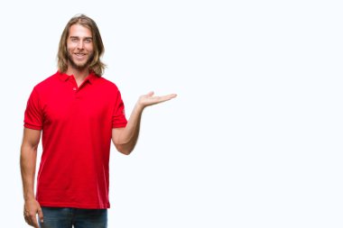 Neşeli sunulması ve kameraya bakarak avucunun ile işaret gülümseyen izole arka plan üzerinde uzun saçlı yakışıklı delikanlı.