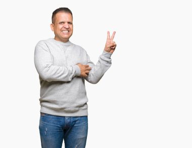 Orta yaş Arap adam mutlu yüz zafer işareti yaparken kameraya göz kırpıyor ile gülümseyen izole arka plan üzerinde spor kazak giyiyor. İki numaralı.