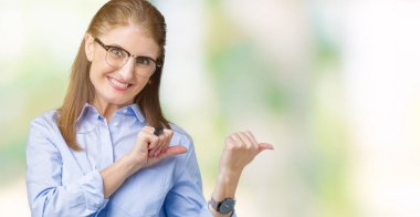 Güzel orta yaş olgun iş kadını üzerinde gözlük takan izole arka plan emin gülümseyen arkasından el ve kadar başparmak ile işaret