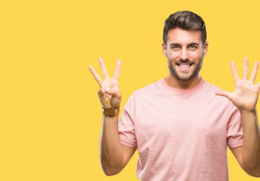 Yakışıklı delikanlı gösterilen ve parmakları ile işaret izole arka plan üzerinde kendinden emin ve mutlu gülümseyerek süre sekiz numara.
