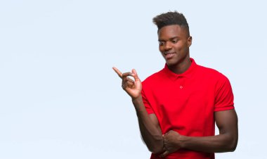 Kameraya bakarak yan el ve parmak ile işaret eden genç Afro-Amerikan adam yüzünde kocaman bir gülümseme ile izole arka plan üzerinde.