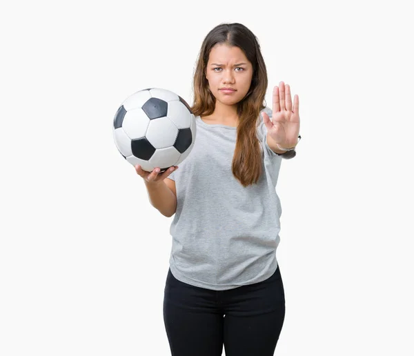 年轻美丽的黑发女子拿着足球在孤立的背景与开放的手做停止标志与严肃和自信的表达 防御姿态 — 图库照片