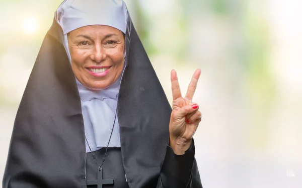 勝利のサインを行うカメラでウィンクしている幸せそうな顔を浮かべて隔離された背景に中年シニア キリスト教カトリック修道女女 — ストック写真