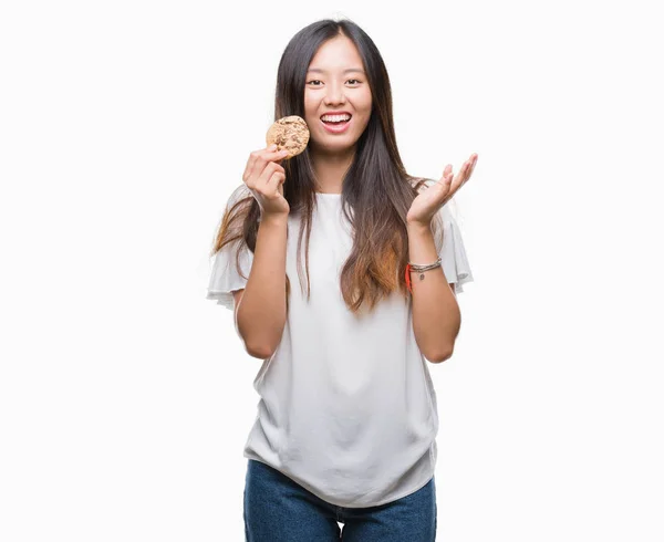 Junge Asiatin Isst Schokoladenkeks Vor Isoliertem Hintergrund Sehr Glücklich Und — Stockfoto