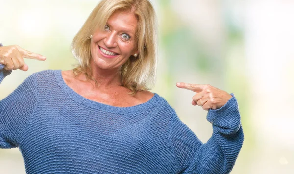 Middle age blonde woman wearing winter sweater over isolated background looking confident with smile on face, pointing oneself with fingers proud and happy.