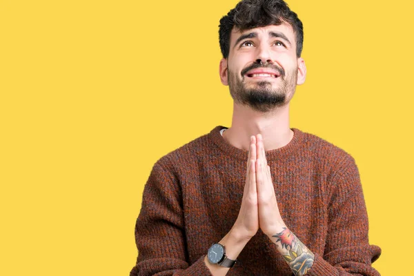 Genç yakışıklı adam yalvarıyor ve umut ifade yüzünde çok duygusal ve endişe ile birlikte elleriyle dua izole arka plan üzerinde kış kazak giyiyor. Bağışlanmak. Din kavramı.