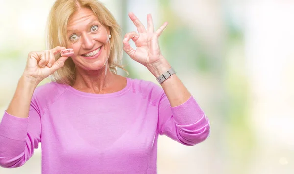 Blonde Frau Mittleren Alters Isst Rosa Makkaron Keks Über Isoliertem — Stockfoto