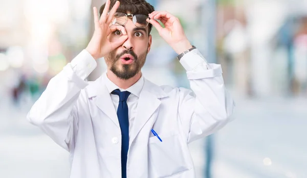 年轻的专业科学家男子穿着白色外套在孤立的背景做确定的手势震惊与惊讶的脸 眼睛通过手指看 不相信的表达 — 图库照片