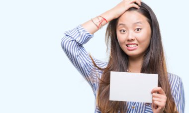 Baş, el ile vurguladı izole arka plan üzerinde boş kartı tutan Genç Asyalı kadın şok utanç ve sürpriz suratla, öfkeli ve sinirli. Korku ve hata için üzgün.