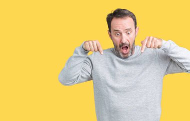 Bir kazak izole üzerinde giyen yakışıklı orta yaş üst düzey adam arka plan işaretleme aşağı reklam, sürpriz yüz ve açık ağız gösterilen parmakları ile