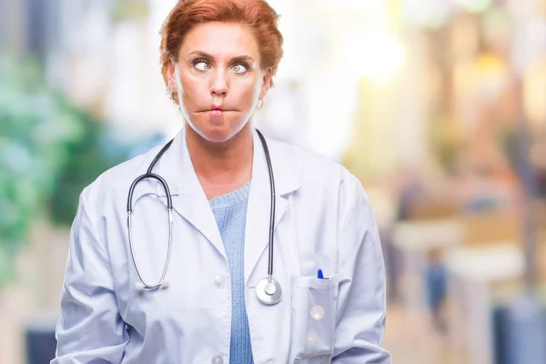 上医療制服を着て先輩の白人医師女性は分離唇 狂気とコミカルなジェスチャーで背景作る魚の顔です 面白い表現 — ストック写真
