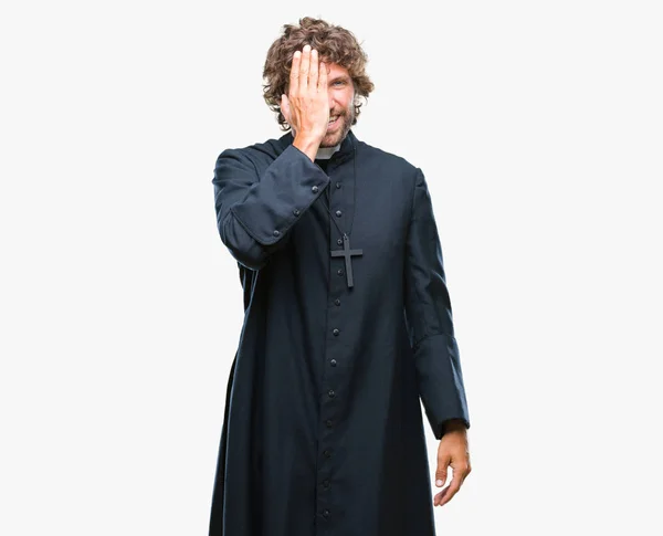 英俊的西班牙天主教牧师在孤立的背景覆盖一只眼睛与自信的微笑在脸上和惊喜的情感 — 图库照片