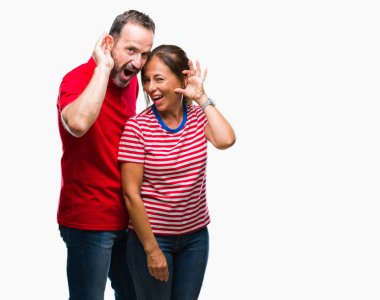 Orta yaş İspanyol çift izole arka plan ile gülümseyen üzerinde aşık bir işitme söylenti ya da dedikodu için dinleme kulak teslim. Sağırlık kavramı.