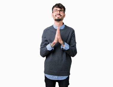 Yalvarıyor ve umut ifade yüzünde çok duygusal ve endişe ile birlikte elleriyle dua izole arka plan üzerinde gözlük takan genç yakışıklı akıllı adam. Bağışlanmak. Din kavramı.