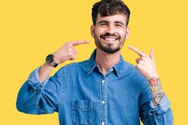 Tecrit edilmiş, güler yüzlü, kendine güvenen, parmaklarını, dişlerini ve ağzını gösteren genç yakışıklı bir adam. Sağlık kavramı.