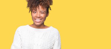 Seksi bir ifadeyle, neşeli ve mutlu yüzünü kameraya bakarak göz kırpıyor izole arka plan üzerinde kış kazak giyen güzel genç Afro-Amerikan kadın.